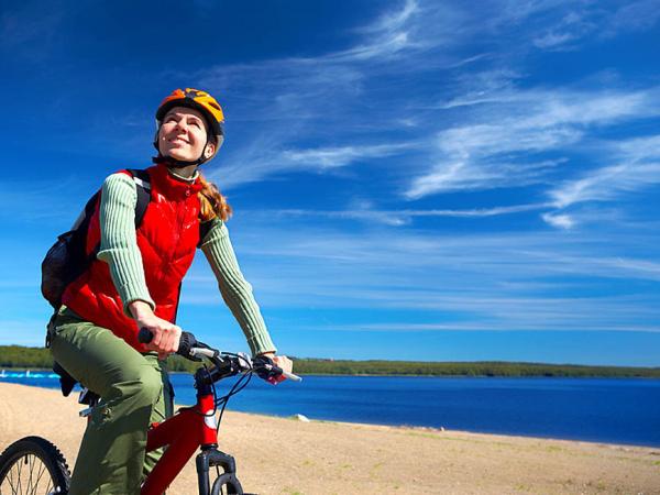 Young smiling woman cycling near the lake 